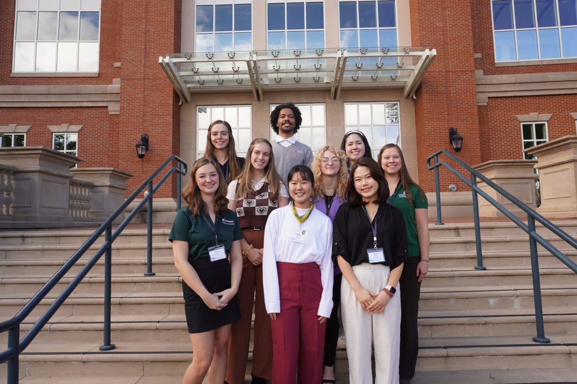 College ambassadors pose for a photo in front of EPIC on a sunny day