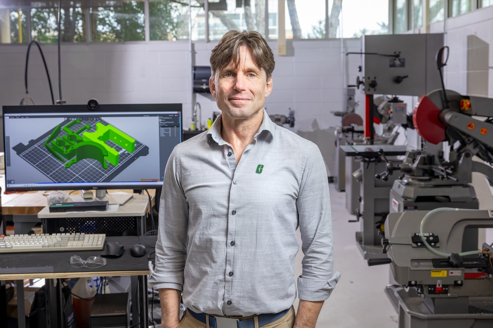 Portrait of Terence Fagan standing near a computer monitor and equipment in the Super Fab Lab