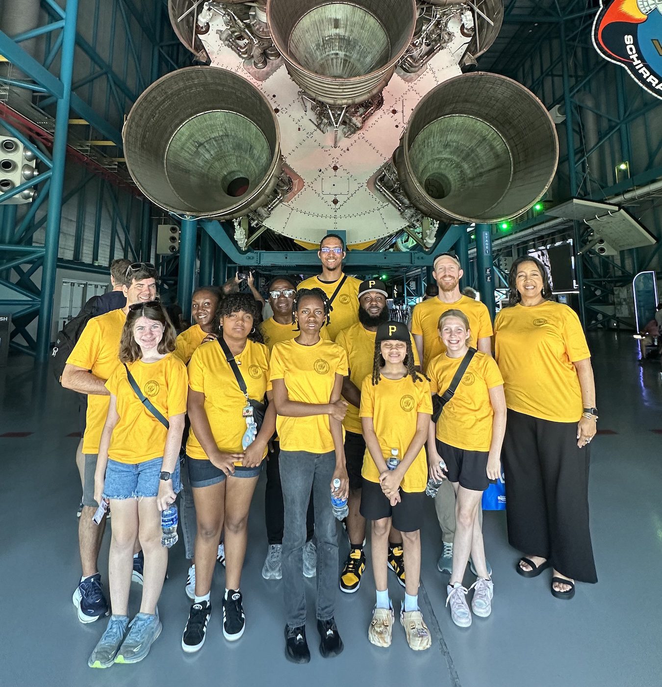Competition winners, the “Bumblebees,” their parents, Grant Williams and Teresa Johnson, William’s mother, in front of a space shuttle’s main engines.