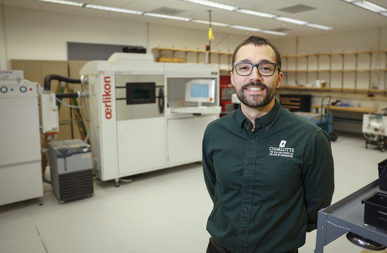 Jaime Berez stands in front of Oerlikon AM additive manufacturing machine.