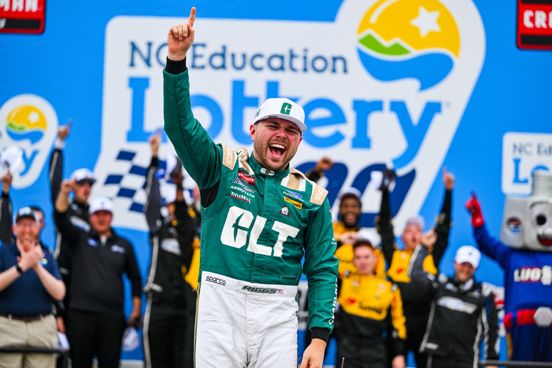 Layne Riggs wearing his Charlotte race suit pointing toward the sky in Victory Lane