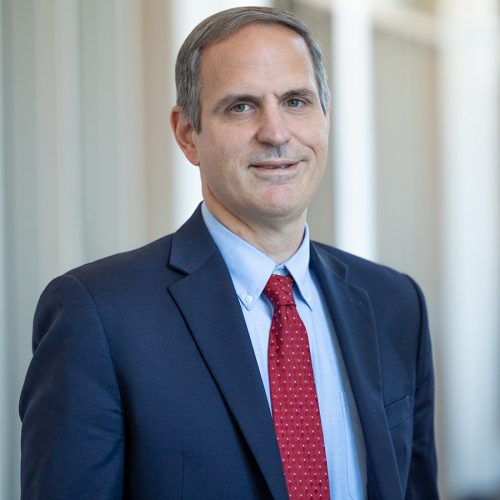 Smiling portrait of Rob Cox wearing a dress coat and tie