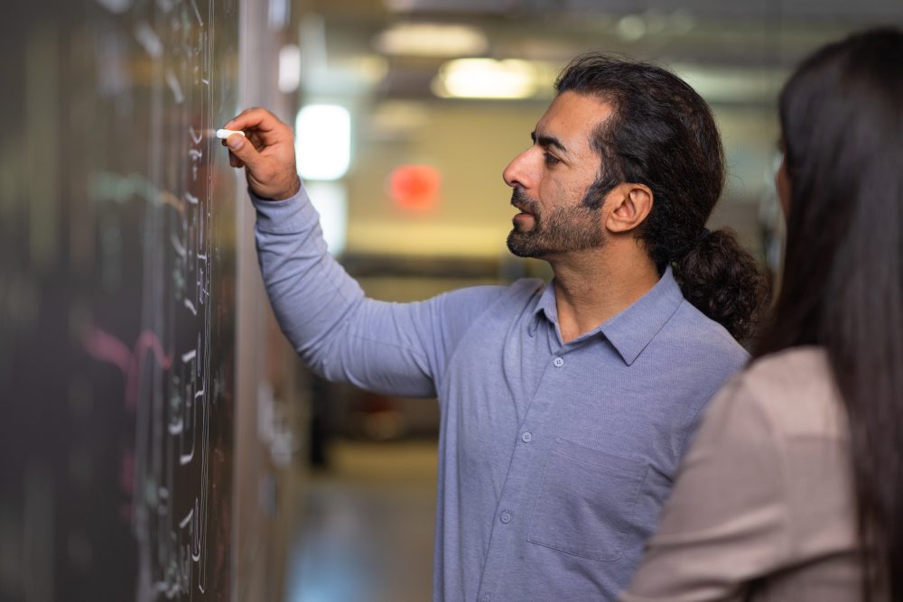 Professor writing on chalkboard