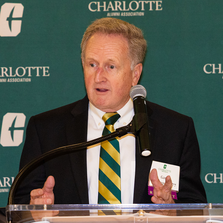 Gary Thompson speaks at a podium during an event hosted by the University of North Carolina Charlotte Alumni Association.